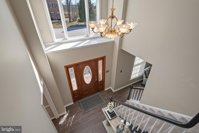 foyer with a towering ceiling, baseboards, an inviting chandelier, and wood finished floors