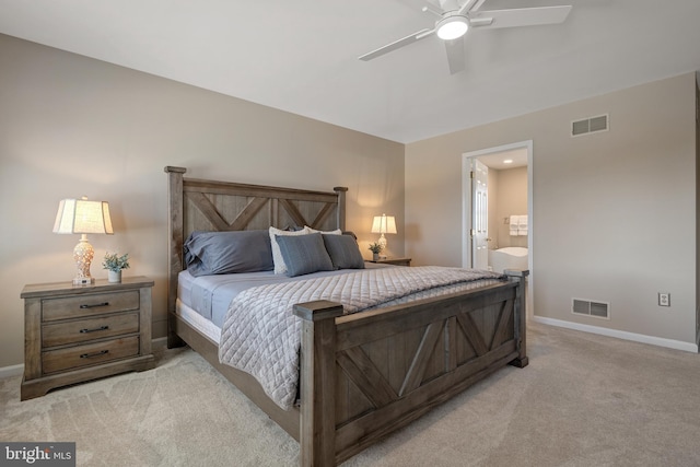 bedroom with ensuite bath, visible vents, light colored carpet, and baseboards