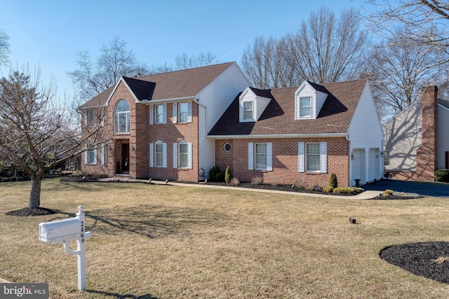 view of front of home with a front yard, roof with shingles, an attached garage, aphalt driveway, and brick siding