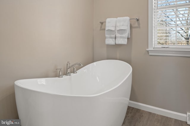 bathroom featuring a soaking tub, wood finished floors, baseboards, and visible vents