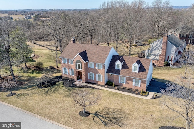 view of front facade with a front lawn, brick siding, and a shingled roof