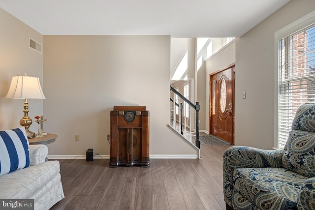 living area featuring stairway, baseboards, visible vents, and wood finished floors