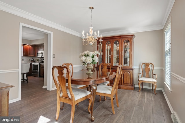 dining room with visible vents, wood finished floors, baseboards, and a chandelier