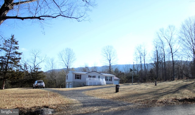 view of front of house featuring a front yard, driveway, and a wooded view