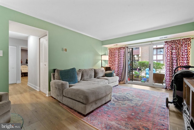 living room featuring ornamental molding, baseboards, and wood finished floors