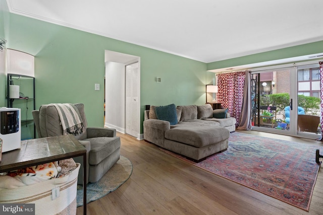 living room featuring baseboards, wood finished floors, and crown molding