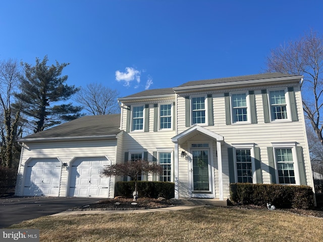 colonial home featuring aphalt driveway and an attached garage