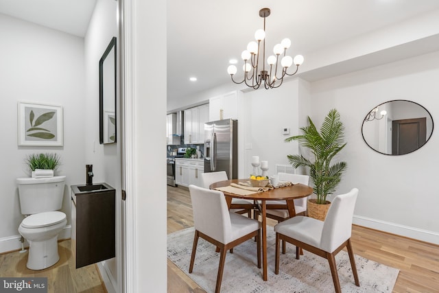 dining room featuring light wood-style floors, a notable chandelier, and baseboards