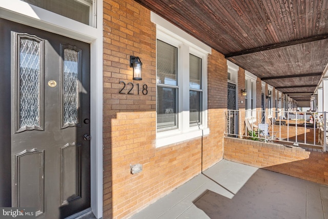 property entrance featuring covered porch and brick siding