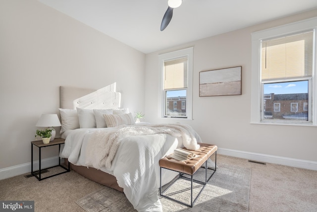 carpeted bedroom with multiple windows, a ceiling fan, and baseboards