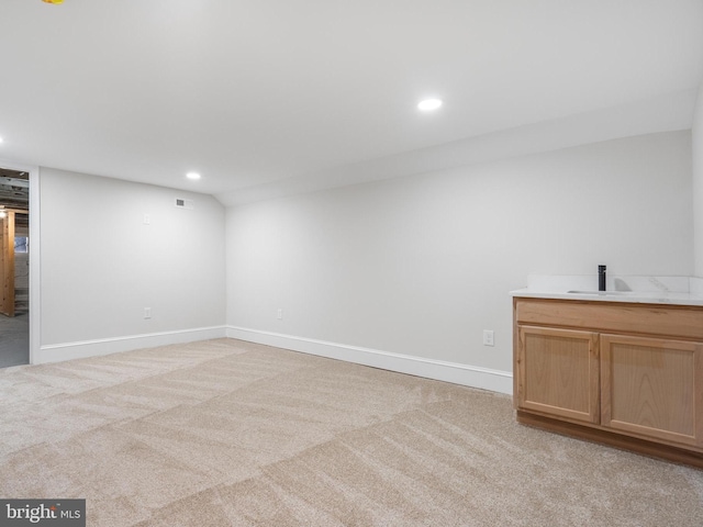 finished basement with recessed lighting, light colored carpet, a sink, and baseboards