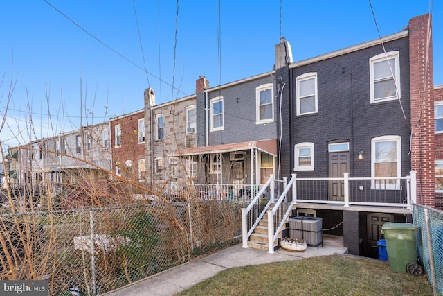 back of house featuring cooling unit, brick siding, and fence