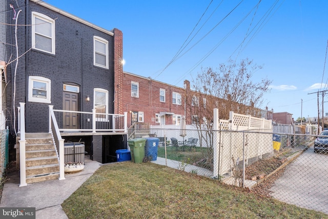 back of property with brick siding, fence, and a yard