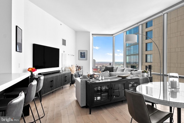 living area featuring light wood-type flooring, visible vents, and floor to ceiling windows