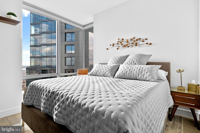 bedroom with expansive windows, wood finished floors, and multiple windows