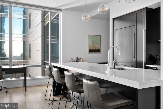 kitchen featuring decorative light fixtures, light wood finished floors, light stone countertops, and a healthy amount of sunlight