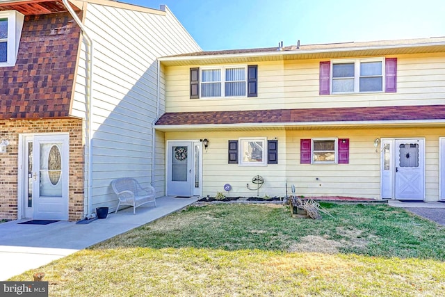 multi unit property featuring a shingled roof and a front yard