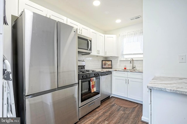 kitchen featuring visible vents, decorative backsplash, appliances with stainless steel finishes, white cabinetry, and a sink