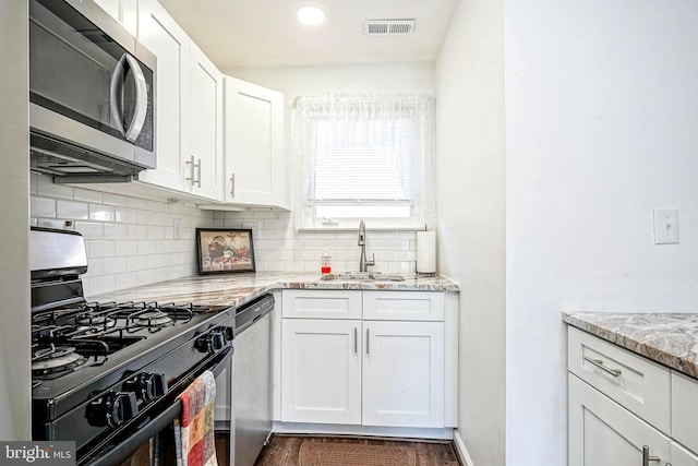 kitchen featuring a sink, visible vents, white cabinetry, appliances with stainless steel finishes, and backsplash