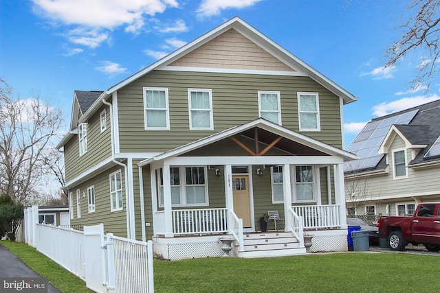 view of front of home with a porch, fence, and a front lawn