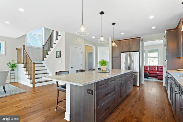 kitchen featuring hardwood / wood-style floors, a kitchen breakfast bar, recessed lighting, and freestanding refrigerator