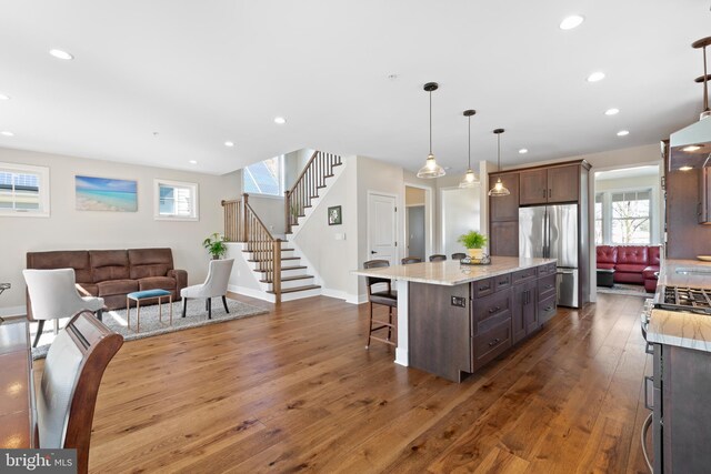 kitchen with a breakfast bar, dark wood-style floors, a center island, freestanding refrigerator, and recessed lighting