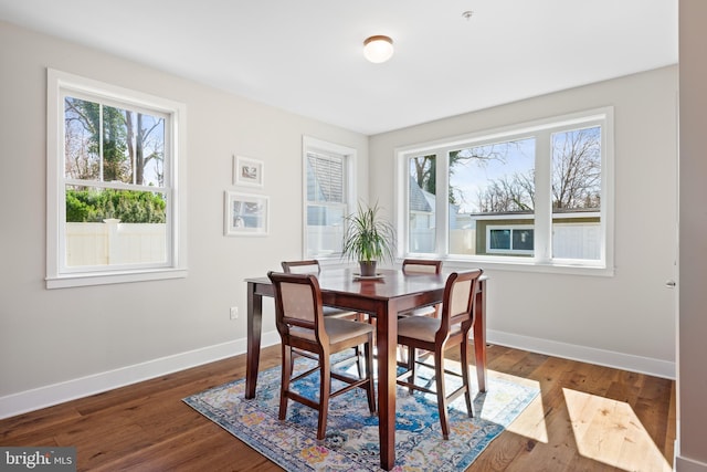 dining area featuring a wealth of natural light, baseboards, and dark wood finished floors