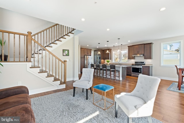 living room with stairway, recessed lighting, wood finished floors, and baseboards