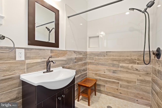 full bath featuring tile walls, vanity, and a tile shower