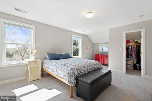 bedroom featuring baseboards, visible vents, vaulted ceiling, light carpet, and a walk in closet