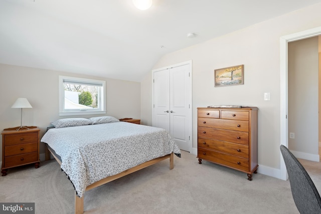 bedroom featuring lofted ceiling, light colored carpet, a closet, and baseboards