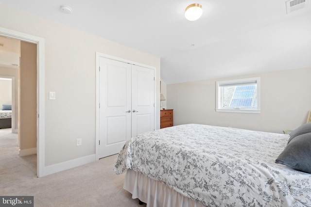 bedroom featuring visible vents, light carpet, lofted ceiling, a closet, and baseboards