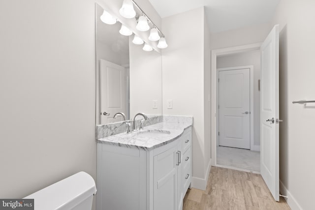 bathroom featuring toilet, vanity, baseboards, and wood finished floors