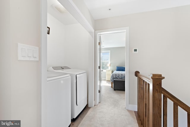 clothes washing area with laundry area, washing machine and dryer, baseboards, and light carpet