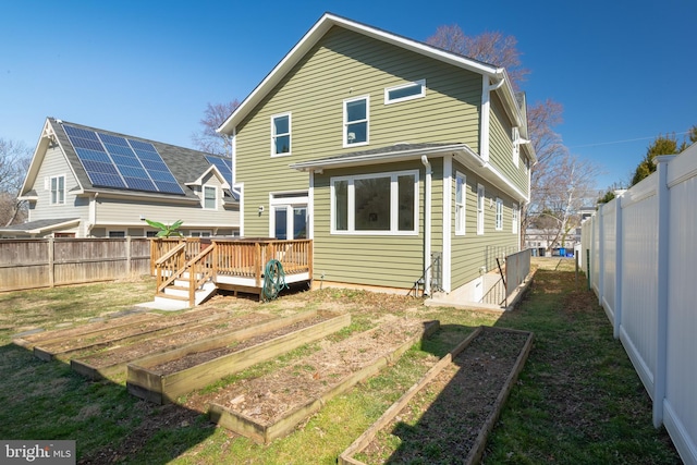 back of house with a deck, a vegetable garden, a yard, and a fenced backyard