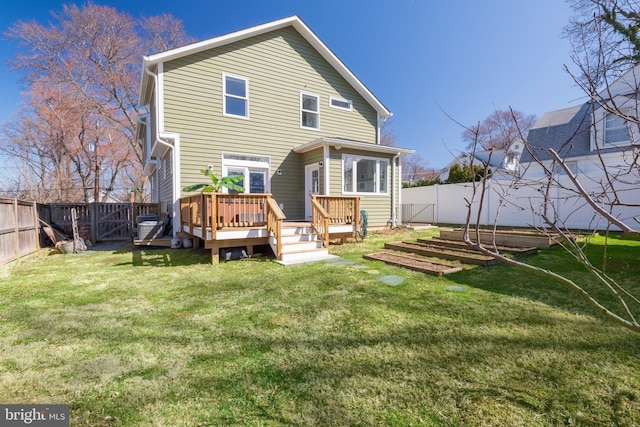 back of house with a lawn, a wooden deck, a fenced backyard, and a gate