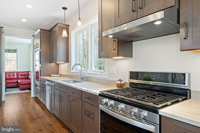 kitchen with under cabinet range hood, plenty of natural light, stainless steel appliances, and a sink