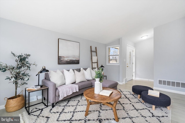 living room featuring light wood-style floors, visible vents, and baseboards