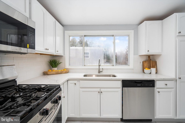 kitchen featuring white cabinetry, appliances with stainless steel finishes, backsplash, and a sink