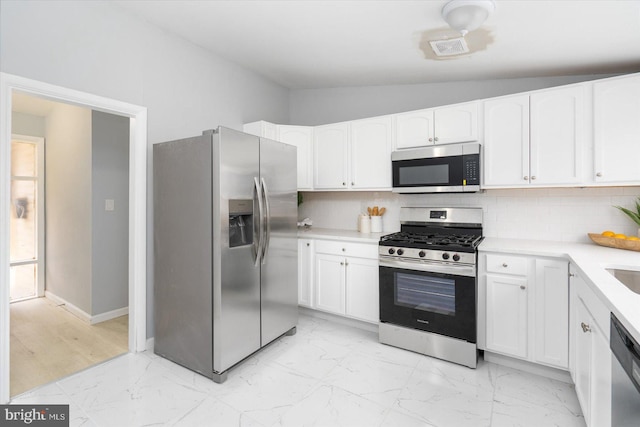 kitchen with appliances with stainless steel finishes, marble finish floor, and backsplash