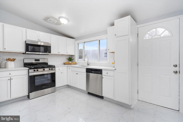 kitchen with lofted ceiling, marble finish floor, stainless steel appliances, and a sink