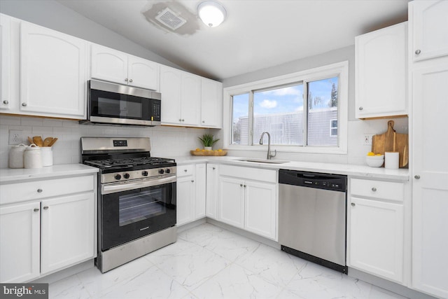 kitchen featuring white cabinets, marble finish floor, stainless steel appliances, and a sink