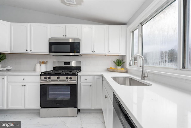 kitchen featuring marble finish floor, stainless steel appliances, white cabinetry, a sink, and vaulted ceiling