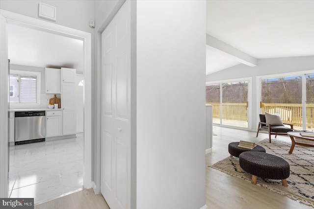 corridor featuring marble finish floor and vaulted ceiling with beams