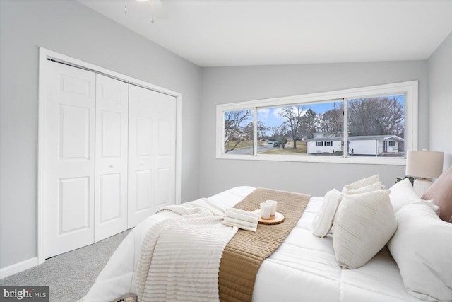 bedroom featuring lofted ceiling, carpet, baseboards, and a closet