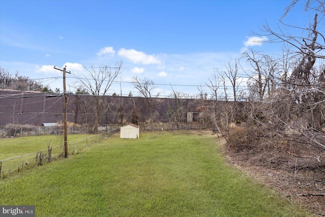 view of yard featuring an outbuilding, a storage unit, and fence