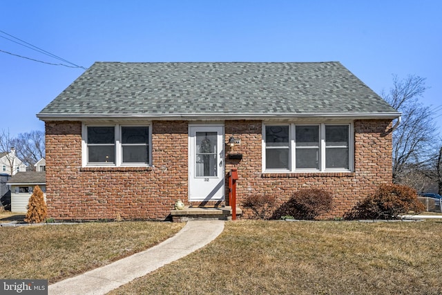 bungalow-style house featuring brick siding, a front lawn, and roof with shingles