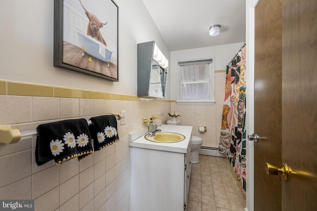 bathroom with a baseboard radiator, toilet, a wainscoted wall, vanity, and tile walls