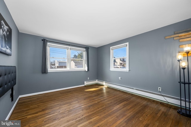 interior space with a baseboard heating unit, baseboards, and wood finished floors