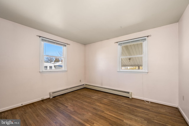 unfurnished room featuring a baseboard heating unit, wood finished floors, and baseboards